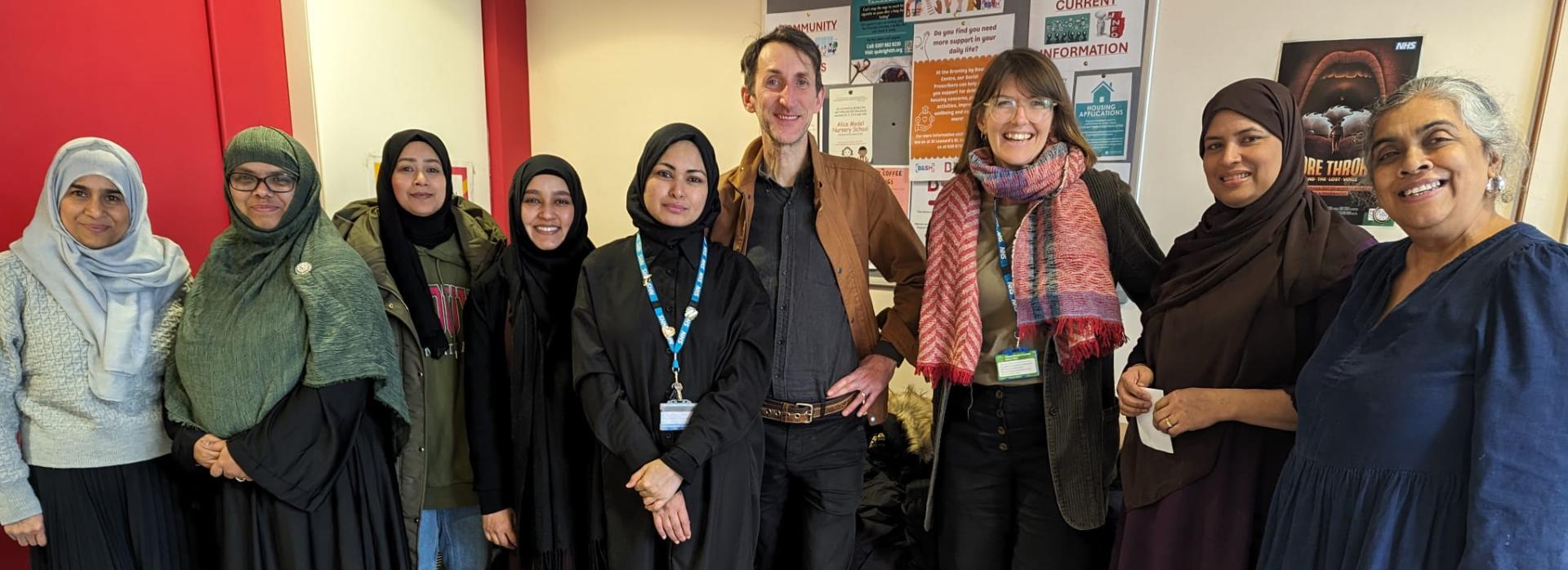 A group of people stand in a semi-circle smiling towards the camera