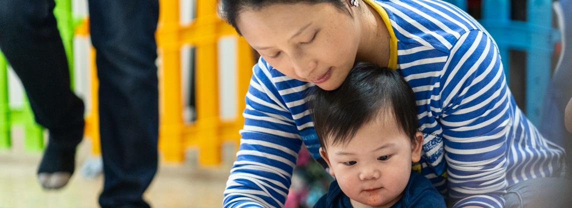 a woman and child play together on a floor surrounded by toys