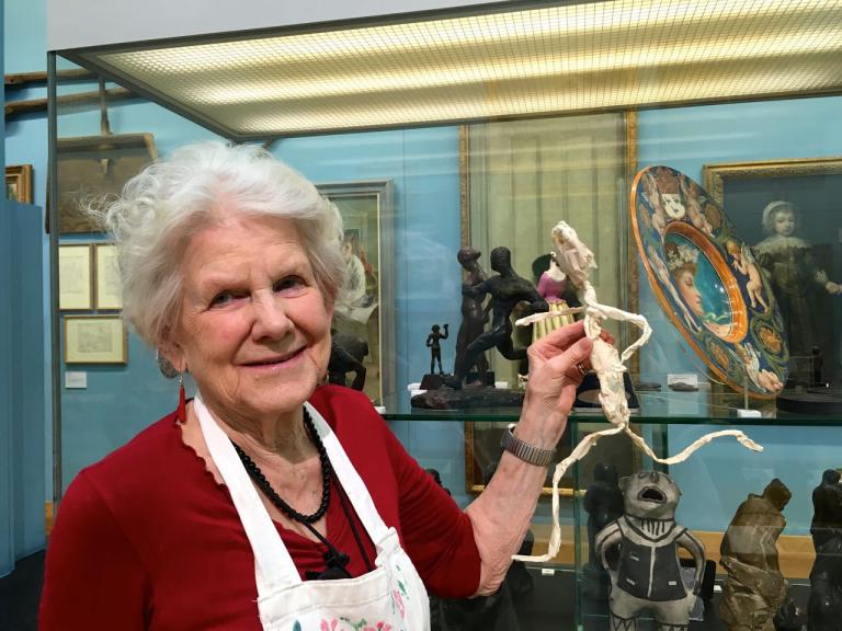 A woman holds a small figure she has made in response to the Beaney's collections
