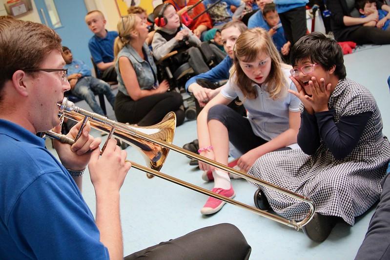 A trombonist plays for two schoolgirls