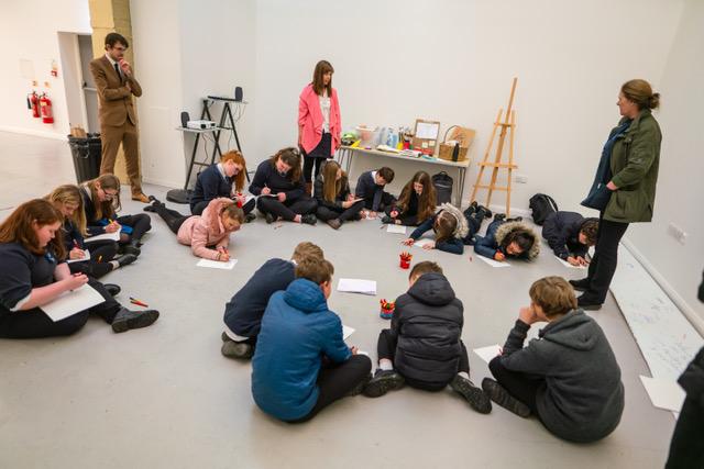 A group of teenagers seated on the floor during a workshop run by Claire Newton