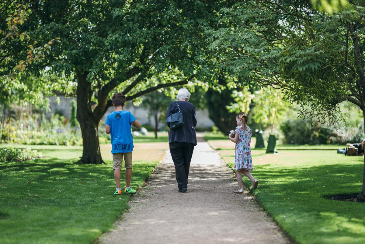 A woman and two children walk down a path in a park