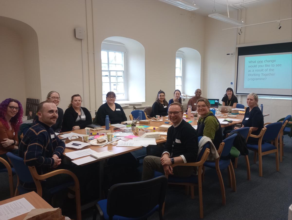 A group of people sit around a table with papers and craft items on it