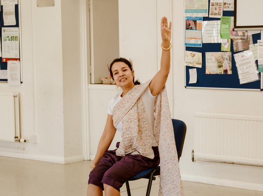 photo of a seated woman raising her left arm 