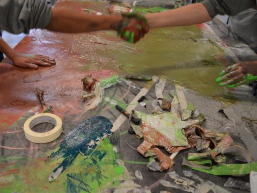 Photo of two people shaking hands, with their hands covered in paint after an art workshop