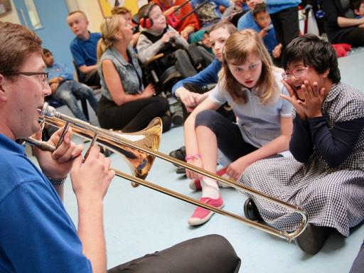 A trombonist plays for two schoolgirls