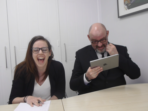 Kelly and a colleague sit at a table, Kelly is laughing