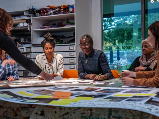 A group of women discuss images laid out on a table