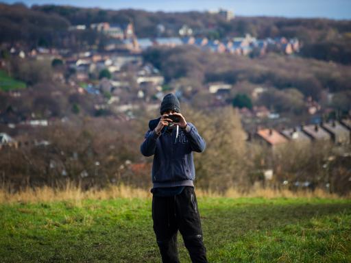 Man About Town participant taking a photo with his phone with Leeds backdrop
