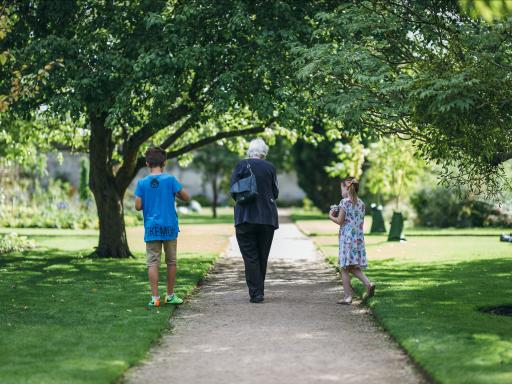 A woman and two children walk down a path in a park