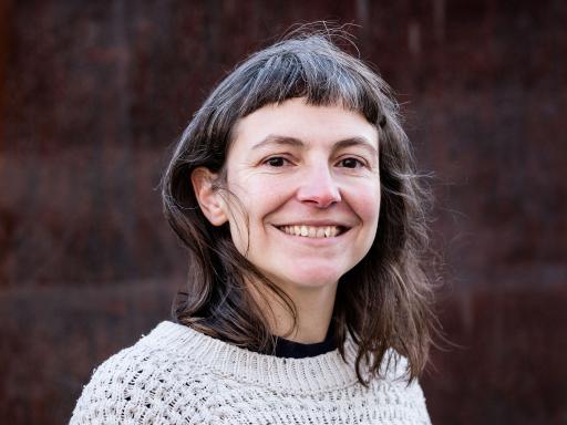 a half-length photo portrait of a woman with dark hair wearing a pale grey sweater