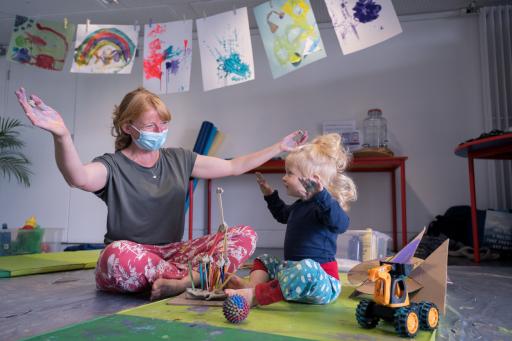 An adult and child with paintings above them