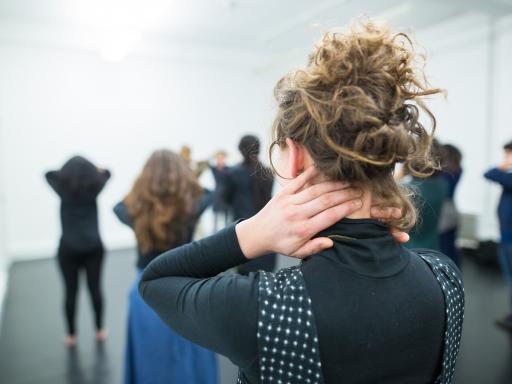 Practitioner holding back of neck in a room with others