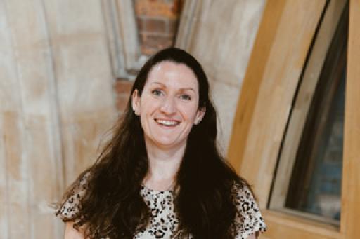 A white woman with long brown hair and a spotted top smiling at the camera