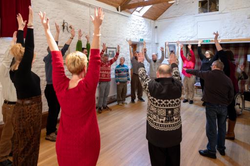 A group of people in a room standing with their hands in the air