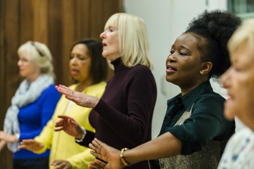 a group of women standing whilst singing and swaying their hands