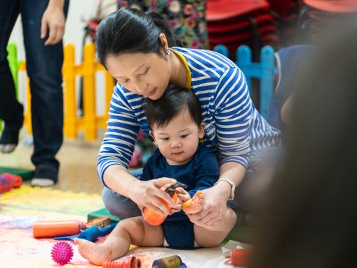 a woman and child play together on a floor surrounded by toys