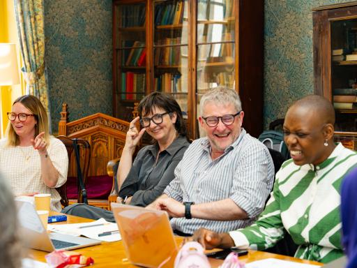 photograph of four people laughing around a table