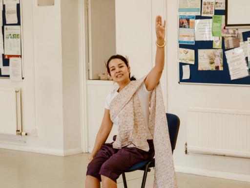 photo of a seated woman raising her left arm 