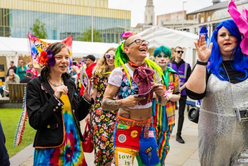 a group of people wearing brightly coloured clothing in an outdoor space smiling and laughing